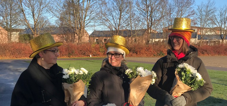 Ann-Mari, Ann-Charlotte och Gunhild med guldhattar på och blommor i famnen